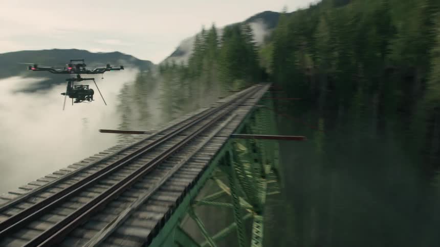 A drone flying over a train bridge
