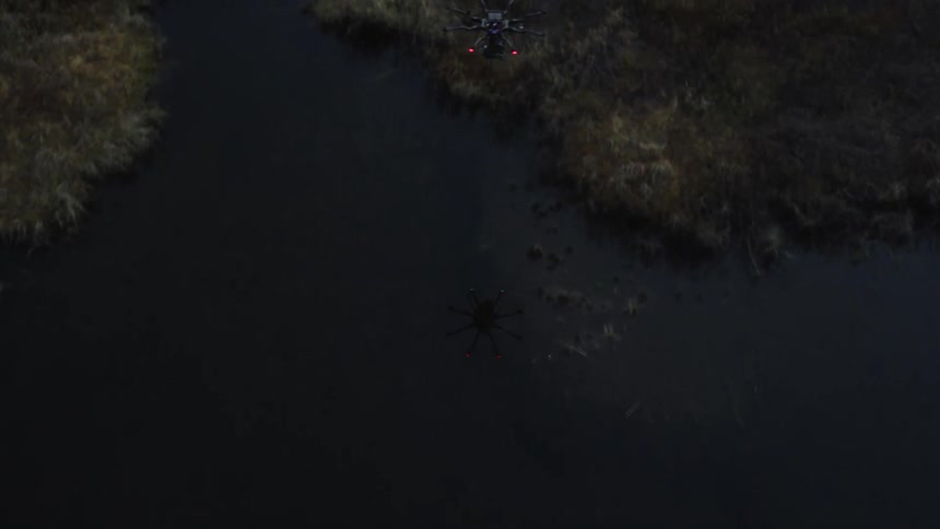 A drone flies over a lake and forested area