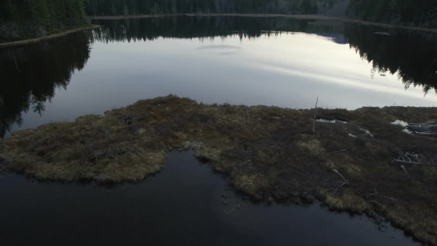 A drone flies over a lake and land