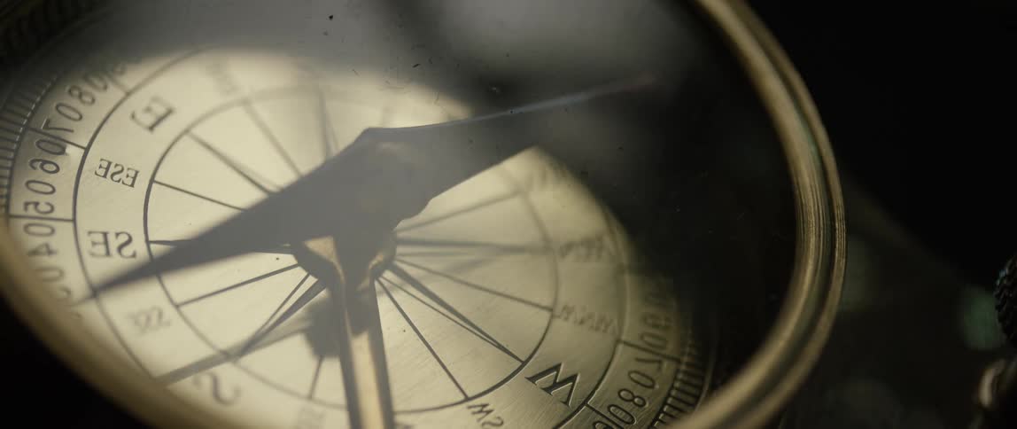 A brass compass engulfed in shadow
