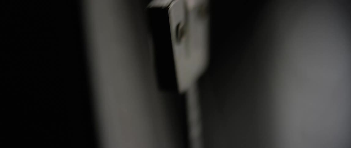 Metronome arm sways back and forth in dimly lit room