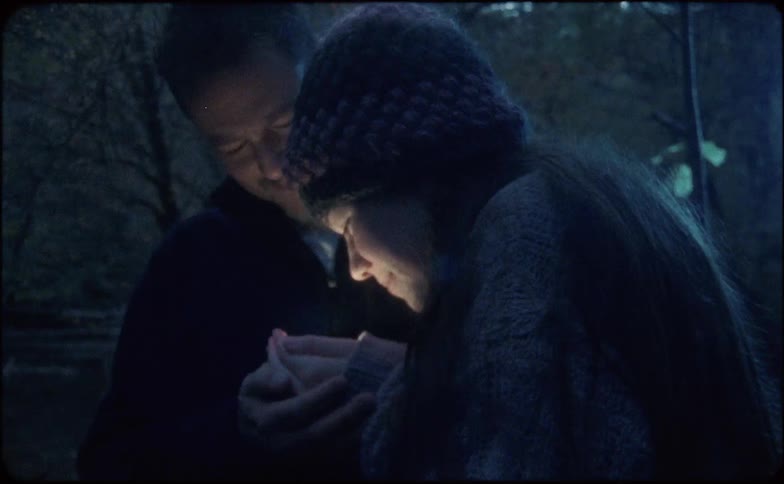 A young girl holds something in her hands and her and her dad look at it