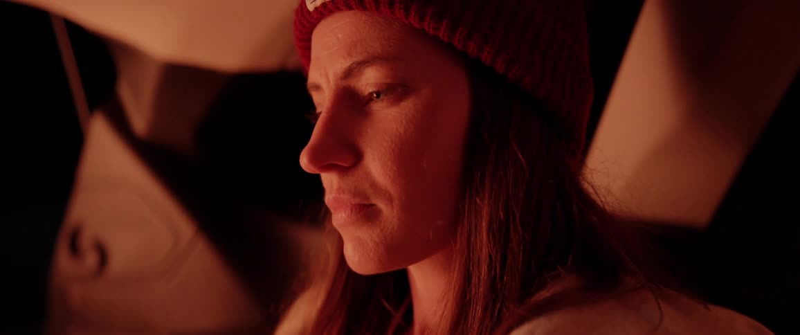 A woman with a hat sitting and staring off into the distance