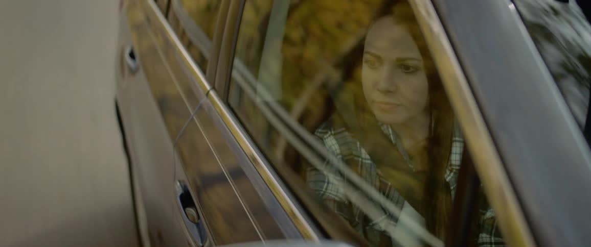 A teenager sits in a car and looks out the window