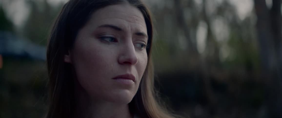 A white woman stands outside and cries