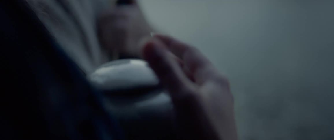 Two women stand together as one takes the lid off an urn