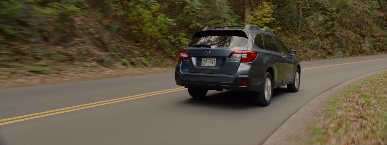 Car drives along the forest highway in the woods