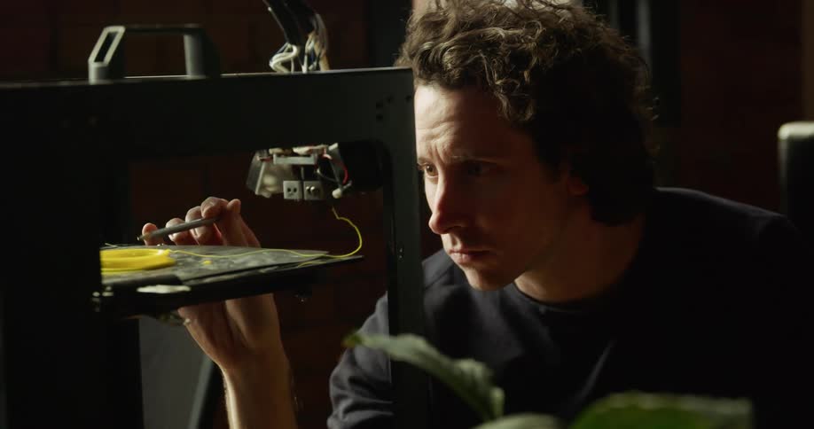 White man using and studying a 3d printing machine