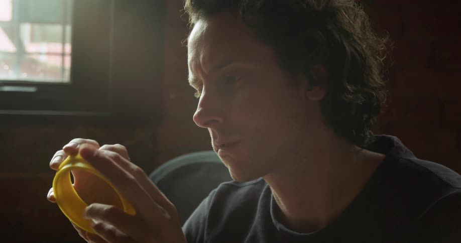 Man inspects a yellow plastic round object as he holds it in his hands