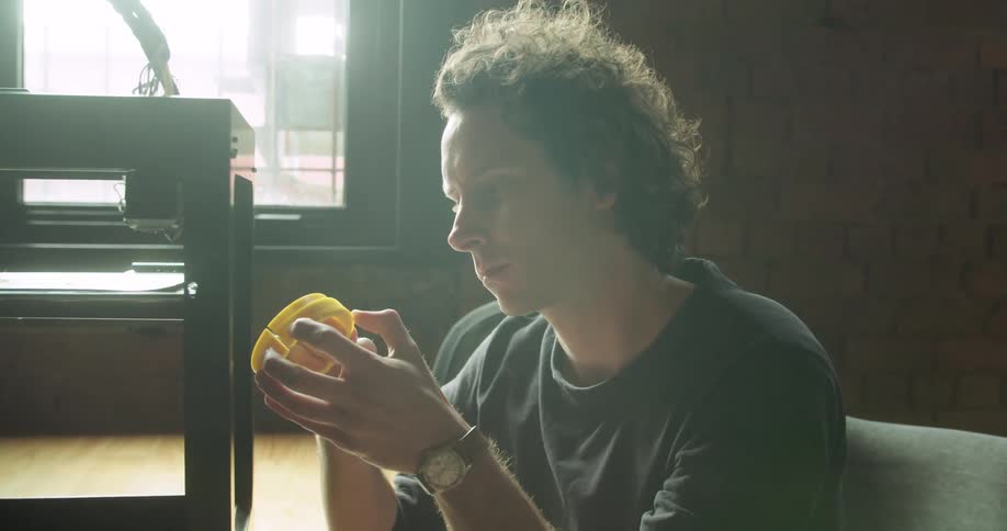 A man pulls some plastic off a 3d printer