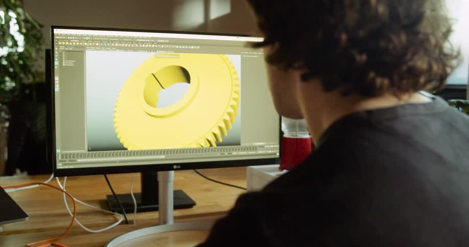 A man sitting in an office is using cad software to design a mechanical part