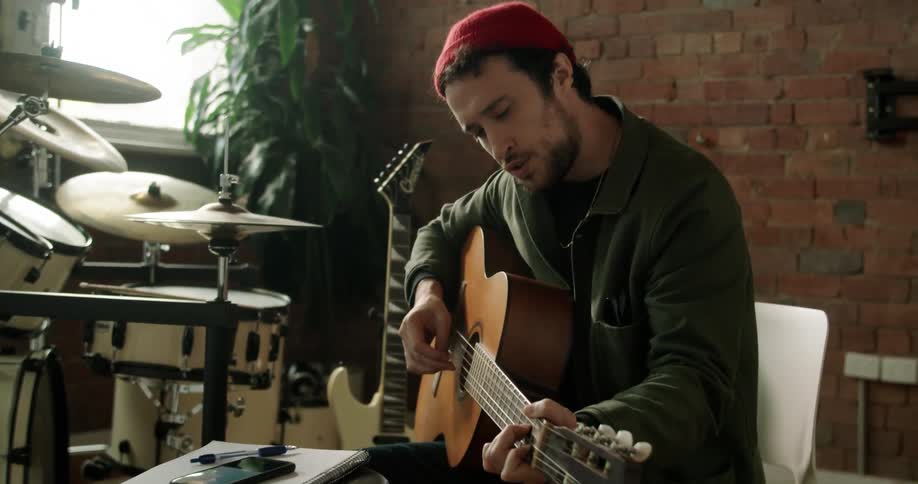 A man sitting in a chair playing an acoustic guitar