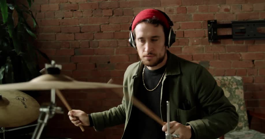 White man playing drum while wearing a headphone