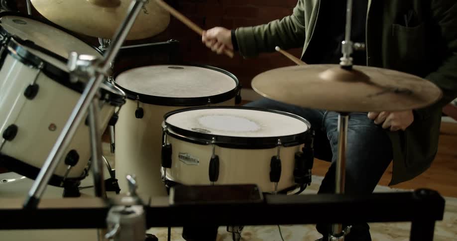 A drummer using a drum set inside during the day