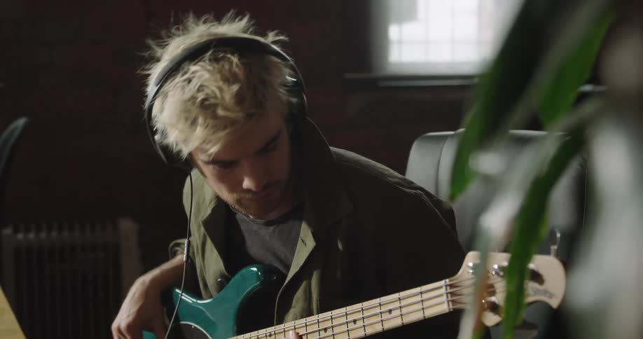 A man plays electric guitar while sitting at a table in a room