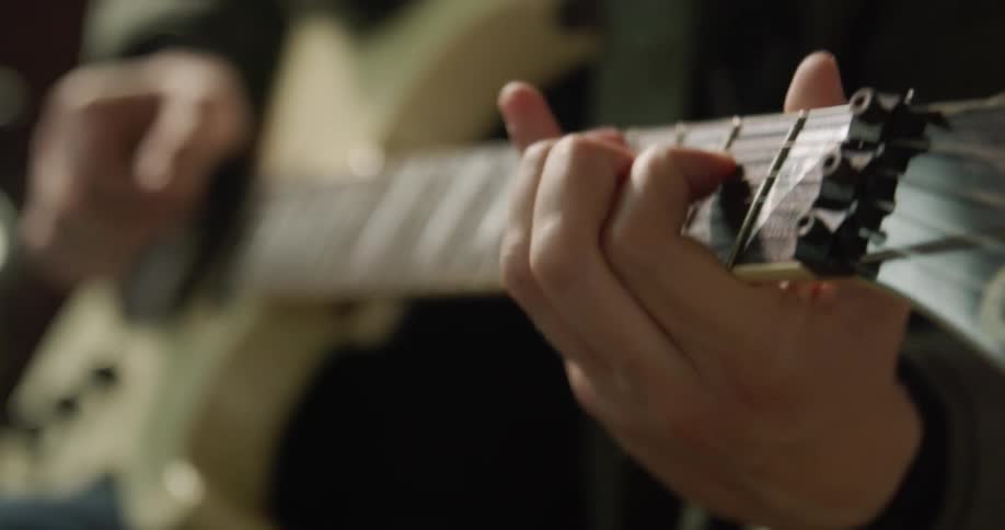 Close up of a person playing a yellow electric guitar