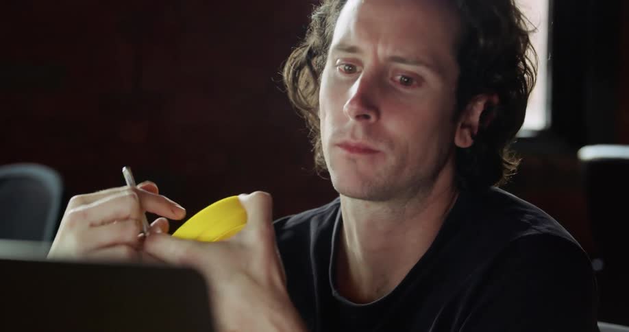 A man in an office looks at his computer and a plastic piece