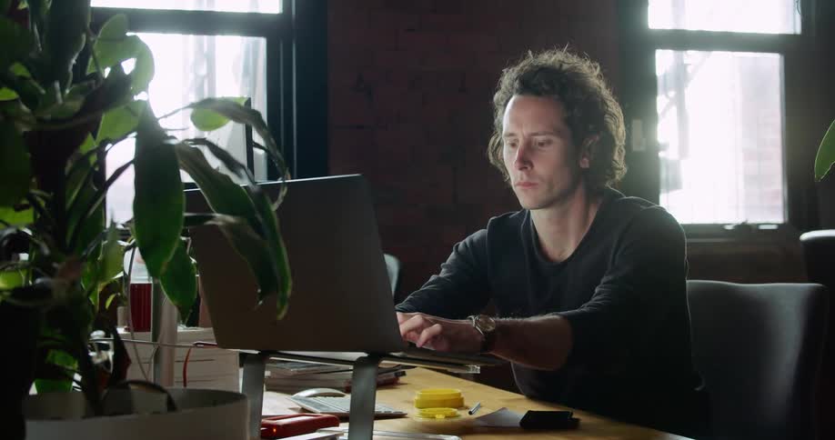A man types on a computer while working at a desk