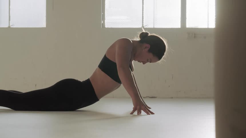 A woman pushes her upper body off the floor doing yoga