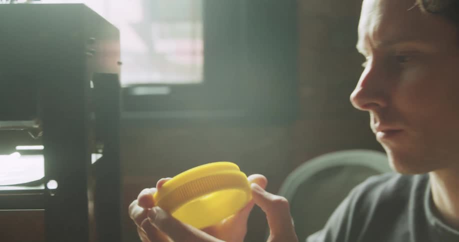 Man removing a lid from 3d printer and inspecting it