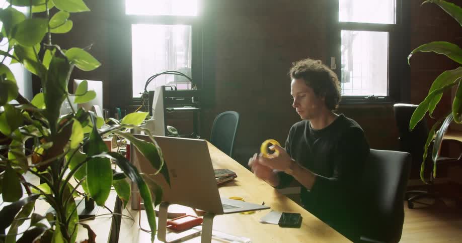 A man holding a plastic ring sits down in a chair and rolls over to his computer