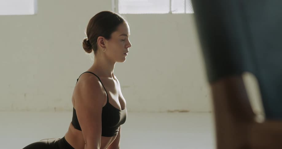 A young woman doing yoga on a yoga mat in a white room