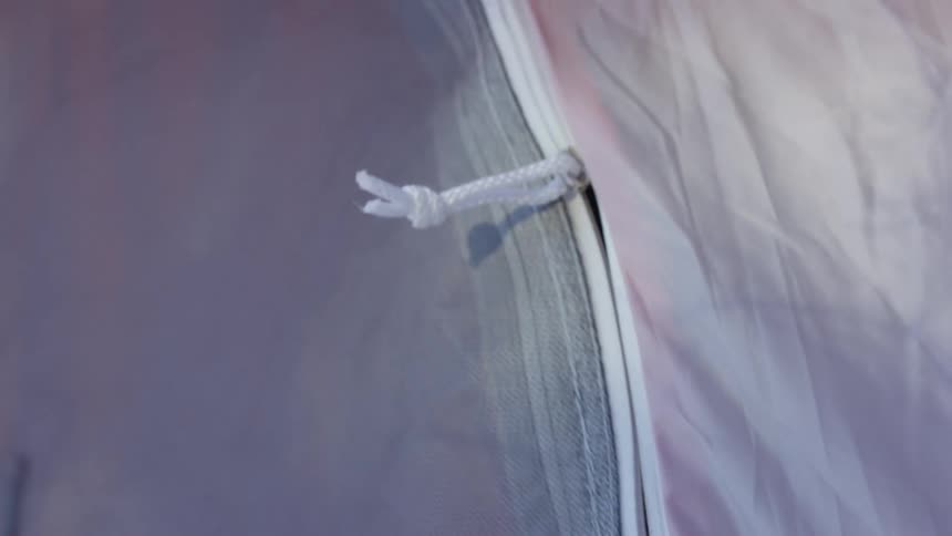 A person opening up a tent zipper from the inside