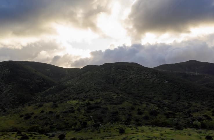 The clouds roll over the green mountain range