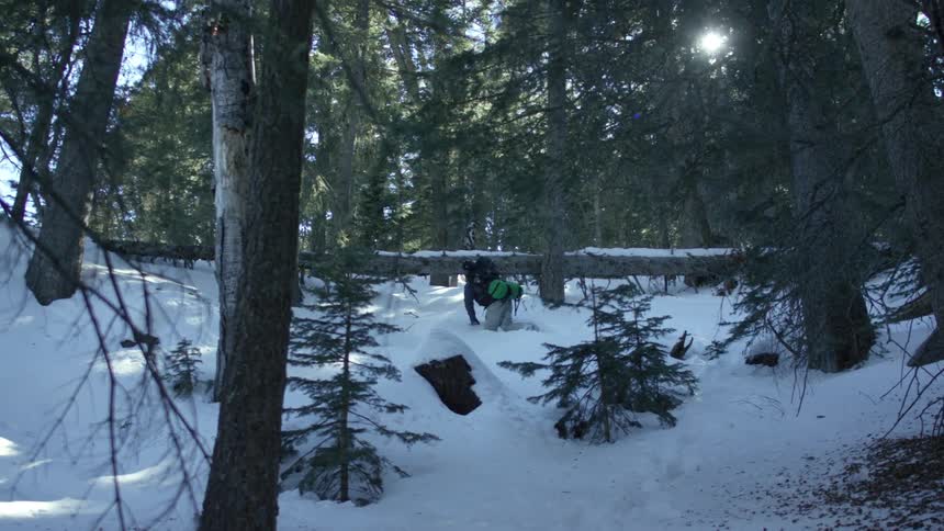 Hiker climbing through the snow in the middle of the forest