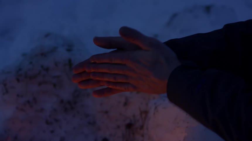 A man warms his hands over a fire