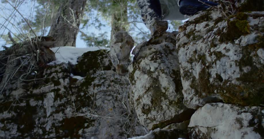 Person climbs rock wall outdoors in the snow knocking down stones