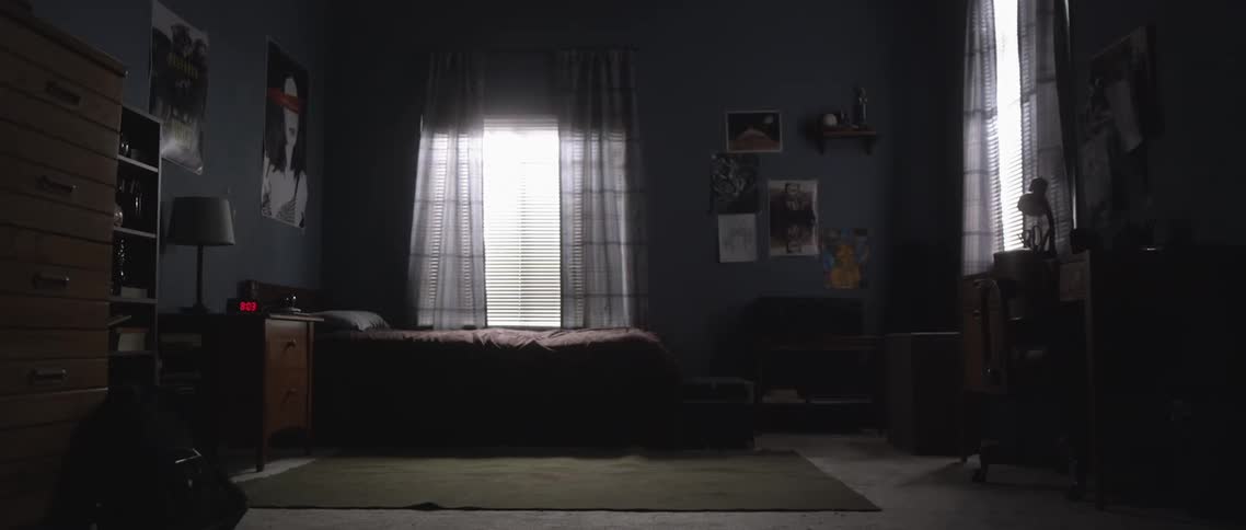 Interior view of an empty dimly lit room with a bed next to the window