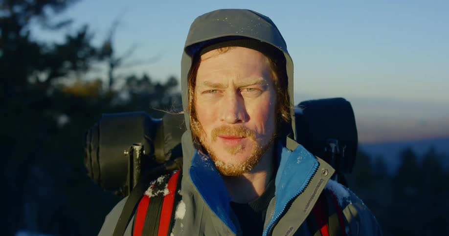 A man with a frosted beard standing outdoors and gazing out of frame