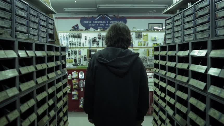 A man walk past store shelves towards a counter