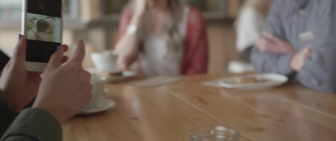 A man uses his phone then passes it over the table to someone else