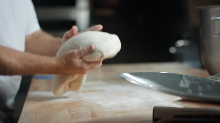 A man flips and kneads dough