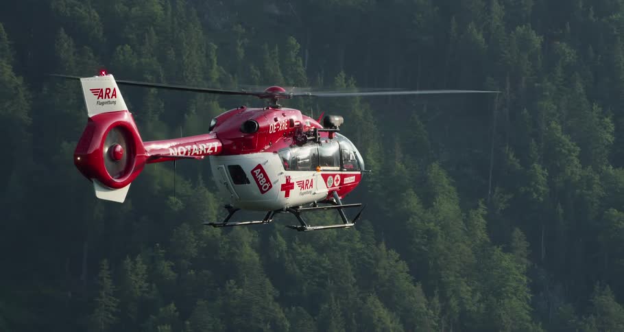 A medical helicopter flies over a forest