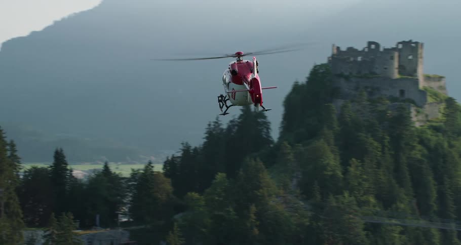 An emergency helicopter flies over the mountains