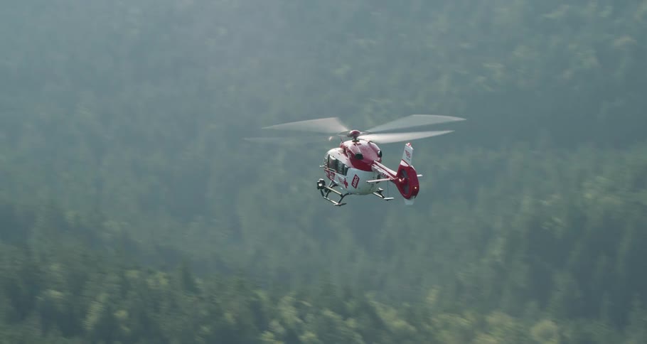 First aid helicopter flying above a forest