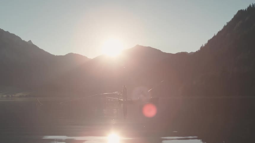 Two people are in a boat on a lake with mountains in the background