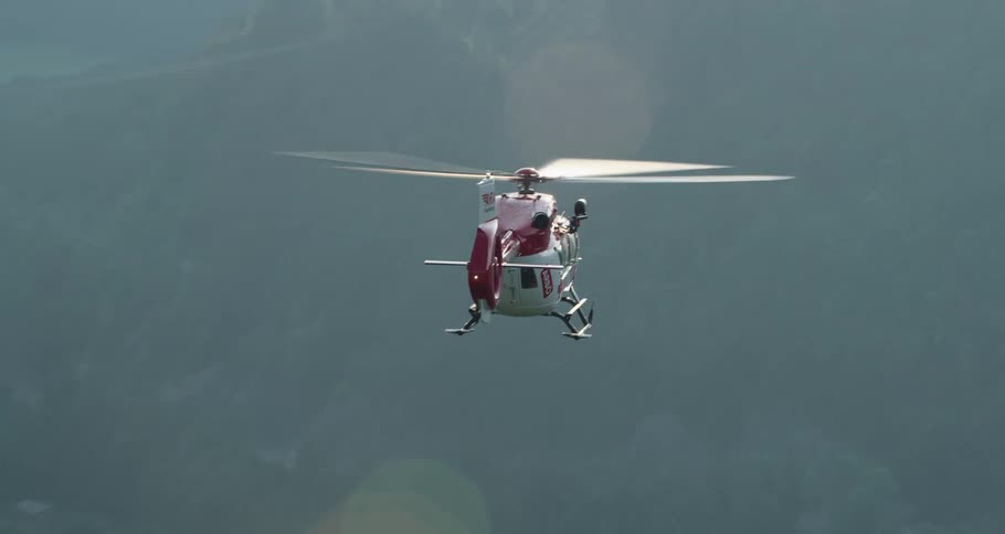 A helicopter flies over hills