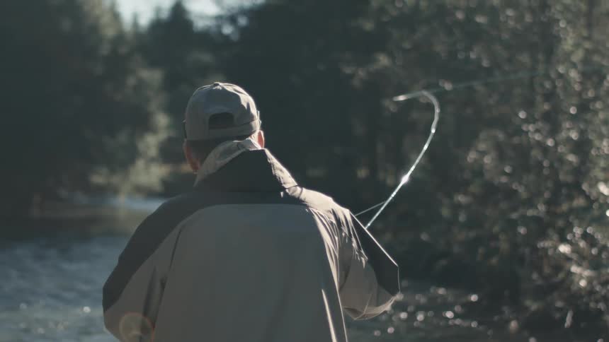 White man fishing at the river outdoors in the middle of the day