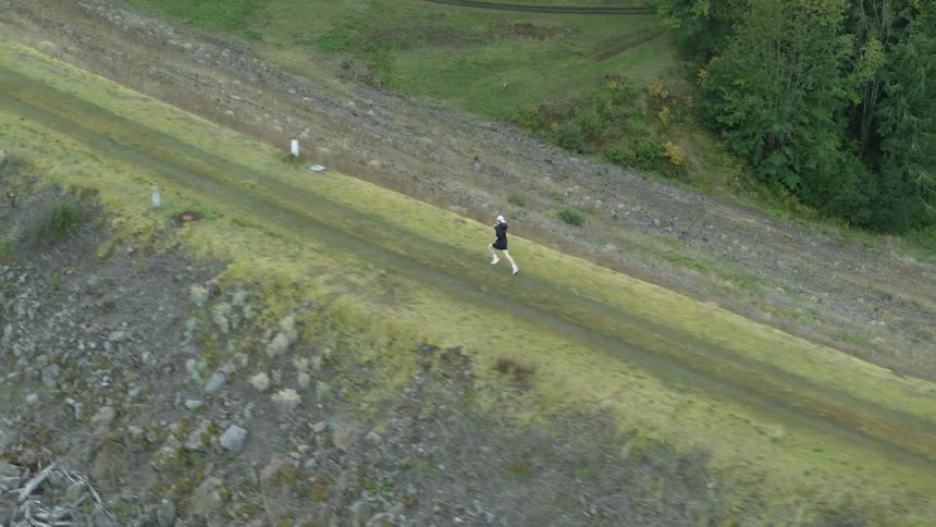 Person running through a dirt road in a forest area