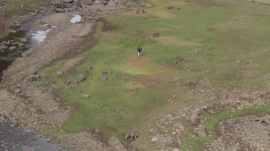 A woman walks across a field using walking sticks