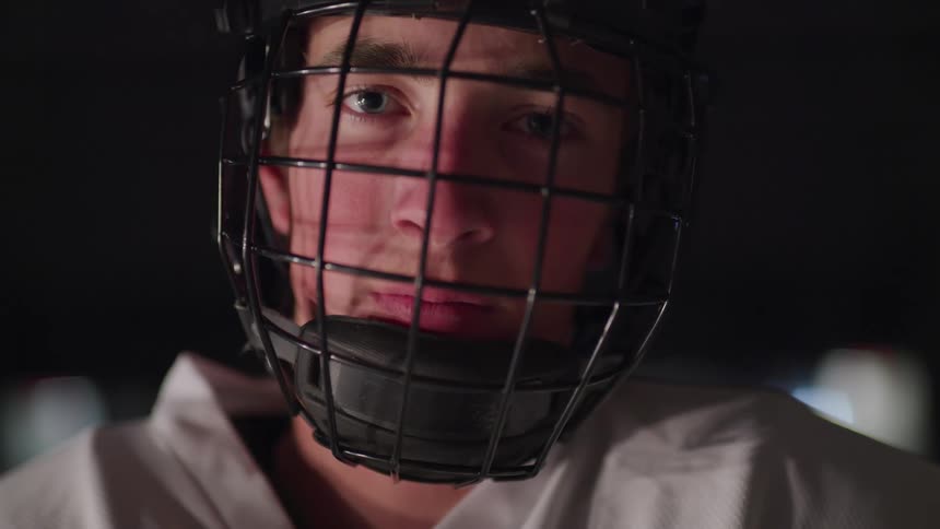 Hockey player stands and looks at the camera in the ice hockey rink