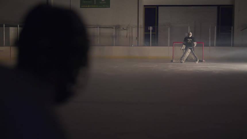 Two men stand on an ice rink wearing ice hockey gear
