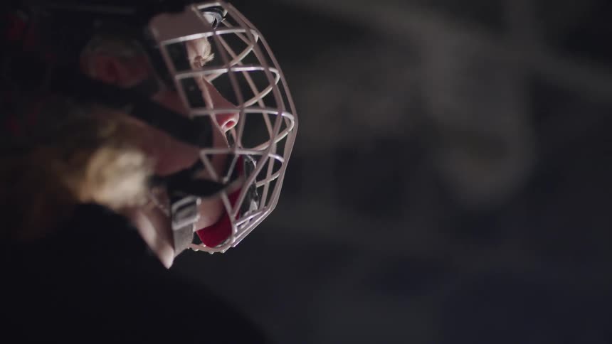 A teenager in hockey equipment breathes in the cold air