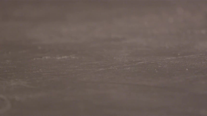 Hockey stick strikes hockey puck stirring up a slight spray of ice