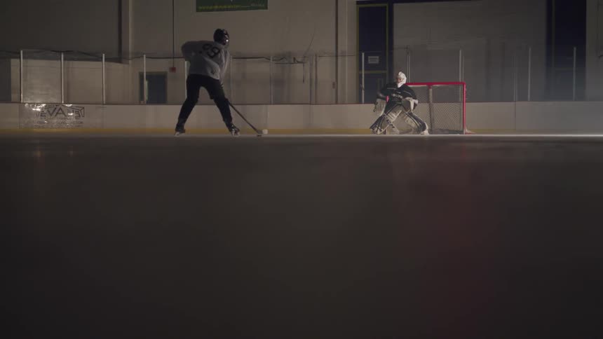 Goaltender stands in the teams goal to try to stop the hockey player from scoring during the game in the ice hockey rink