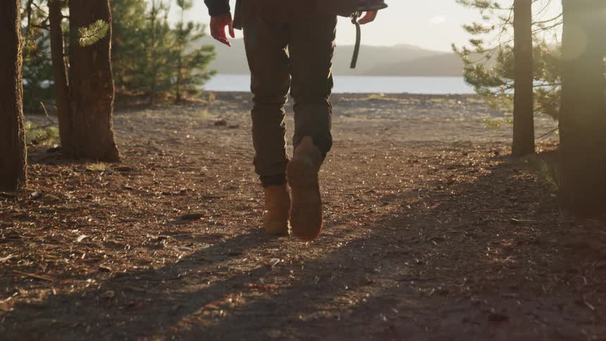 Male hiker walks up to the lakeside at sunset